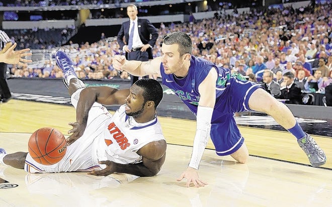 Florida's Patric Young passes the ball away from Florida Gulf Coast's Brett Comer during the second half of a regional semifinal game in the NCAA college basketball tournament, Friday, March 29, 2013, in Arlington, Texas. (AP Photo/David J. Phillip)