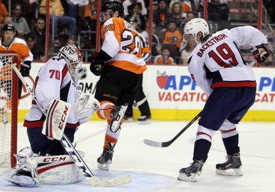 Washington Capitals goalie Braden Holtby, left, holds on to the puck shot by Philadelphia Flyers' Claude Giroux , center, while Capitals' Nicklas Backstrom (19) watches in the second period of an NHL hockey game, Sunday, March 31, 2013, in Philadelphia. (AP Photo/Tom Mihalek)