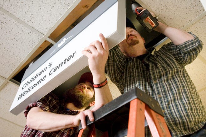 Zach Hill (left) and Jeriomy Guernsey of Jarob Design in Grand Rapids, Mich., install a sign Thursday, March 28, 2013, at First Free Church in Rockford.