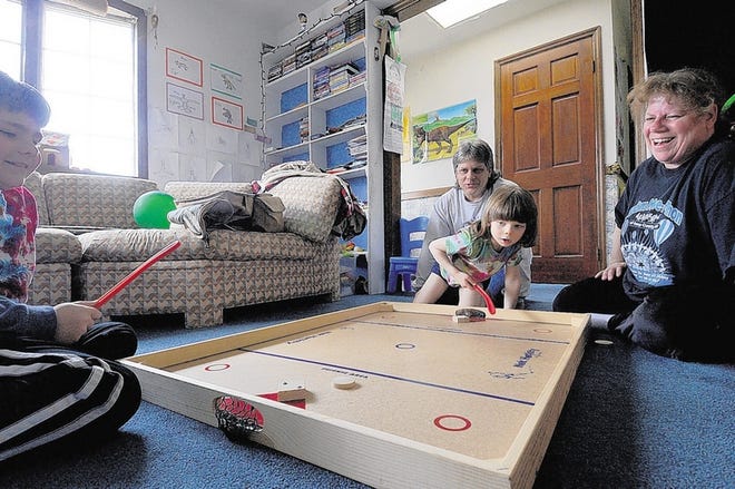 Enjoying a lively game of tabletop hockey are 6-year-old Eric Orzell, center, and his big brother, 9-year-old Jason, as parents Stacey and Brian watch from the sidelines. Eric, who has autism, was the 2011 "poster boy" for New York state's Autism Awareness Month.