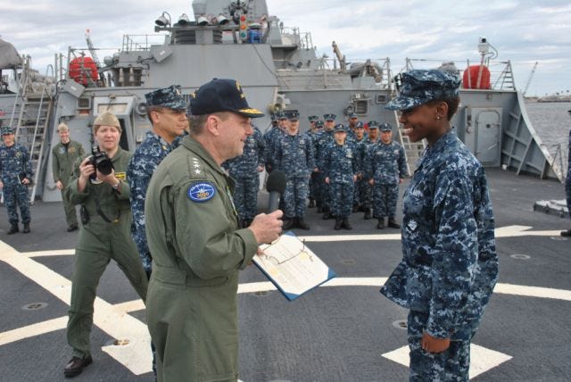 Adm. Bill Gortney, Commander, U.S. Fleet Forces, presents Ship Serviceman Destiney Canada with the Navy and Marine Corps Achievement Medal during an all-hands ceremony on the flight deck.