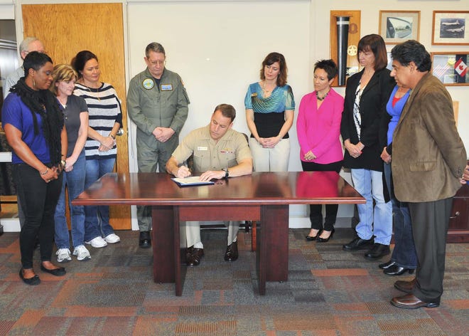 Rear Adm. Jack Scorby Jr., commander, Navy Region Southeast (CNRSE), signs a proclamation in support of sexual assault awareness in front of members of the CNRSE Family Advocacy Program on March 29. The proclamation recognizes April as Sexual Assault Awareness Month throughout the Southeast Region. Scorby also signed a proclamation in support of child abuse prevention and the Month of the Military Child.