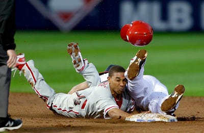 Philadelphia Phillies' Ben Revere , left, loses his helmet while colliding with Atlanta Braves' Andrelton Simmons, right, on a dive back to second base after leading off in the third inning of an opening day baseball game, Monday, April 1, 2013, in Atlanta. (AP Photo/David Goldman)
