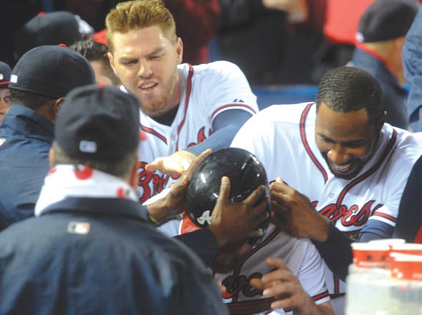 Atlanta’s Evan Gattis, center, is mobbed by teammates after he hit a home run against Philadelphia on Wednesday. (John Amis | Associated Press)