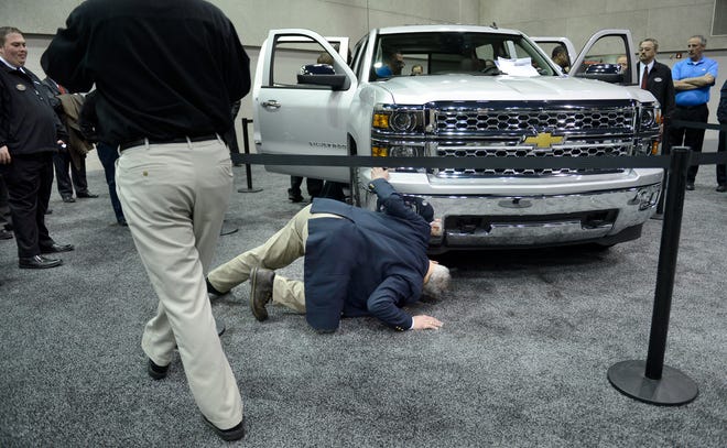 A member of DriveChevy.com, a group of area Chevrolet dealers, checks under a pre-production 2014 Chevy Silverado in a preview Friday morning of the Central Illinois Auto Show at the Peoria Civic Center.