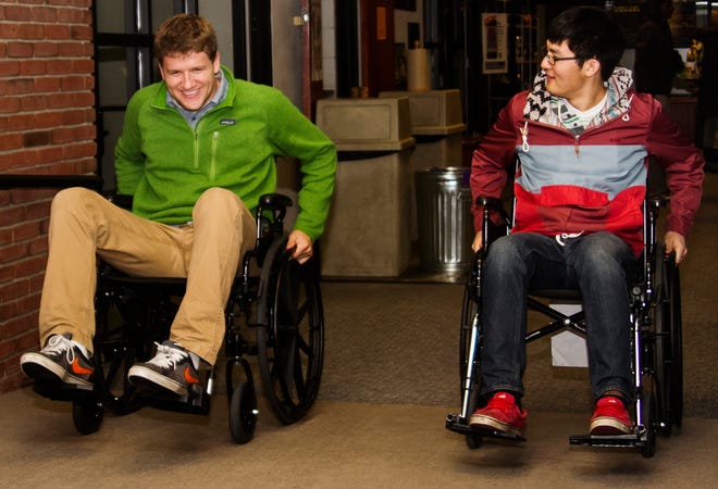In a simulation of living life with a mobile disability, Zack Williams, left, laughs out of frustration as Chris VanKampen, right, agrees on their difficult task of going up the wheelchair ramp in Hope’s Kletz Dining Commons on Tuesday, April 9, 2013. Students were encouraged to participate in the weeklong disability awareness. 
Kelly Gampel/Sentinel Staff