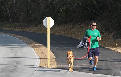 Matt McMahon with friend Jazz jog along the new and improved bike path adjacent to Coast Guard Road in Emerald Isle. The town wants citizen input on a possible 1-cent property tax increase to pay for several community improvement projects.