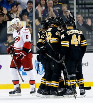 Dennis Seidenberg (44) and Jaromir Jagr (68) celebrate with teammates after Brad Marchand scored his second goal as Carolina's Jordan Staal (11) skates away in the first period of the Bruins' win.