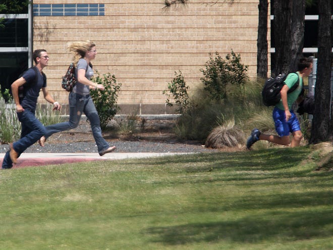 Students run from the Lone Star College's Cy-Fair campus in Cypress, Texas, where a student went on a building-to-building stabbing attack Tuesday. The attacker wounded at least 14 people before being subdued and arrested, authorities said. (AP Photo/Houston Chronicle, James Nielsen)