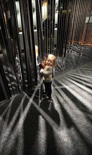 Sydney Schafer, 2, of Bradford, Penn. plays with "Fractured Bodies," part of the Boston Children's Museum new exhibit called "Arrangements of Motions'' featuring six interactive sculptures that demonstrate different kinds of kinesthetic and perceptual effects.