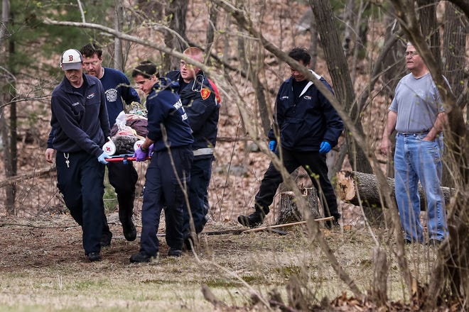 EMS and paramedics carry a 79-year-old woman who was pinned under a 10 inch diameter tree she was attempting to cut down at 187 Tuner Rd. in Holliston on Thursday. The woman was taken by LifeFlight to a trauma center and her condition was unknown.
