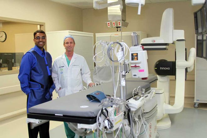 Baptist Medical Center cardiologist Ruple Galani (left) and interventional radiologist Steve Shirley stand with new equipment in the center.