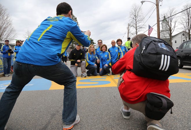 Members of a Chicago area running club, the Yankee Runners, pose for pictures at the starting line of the Boston Marathon in Hopkinton on Sunday