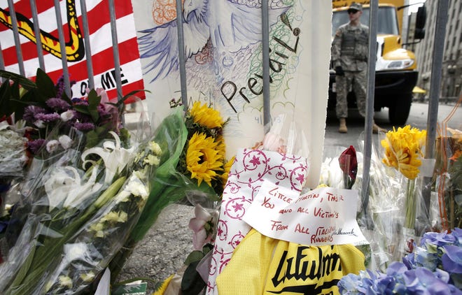 Flowers and a note to the victims signed "From All Italian Runners" are placed by a Boston police barricade near the finish line of the Boston Marathon in Boston, Tuesday, April 16, 2013. The bombs that ripped through the crowd at the Boston Marathon, killing three people and wounding more than 170, were fashioned out of pressure cookers and packed with metal shards, nails and ball bearings to inflict maximum carnage, a person briefed on the investigation said Tuesday.