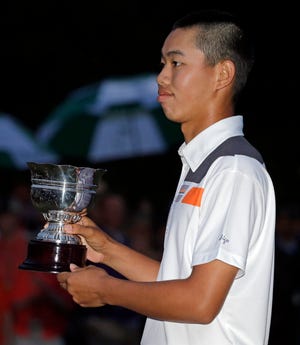 Amateur Guan Tianlang of China holds the amateur trophy after the Masters golf tournament Sunday, April 14, 2013, in Augusta, Ga.