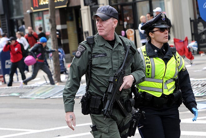 An officer from the Transit Police Special Operations unit carries an automatic weapon after two bombs exploded near the finish line of the Boston Marathon. Daily News STAFF Photo by Ken McGagh