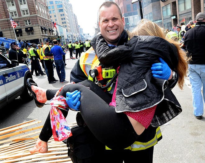 A Boston firefighter carries an injured spectator from the scene following an explosion at the Boston Marathon finish line.