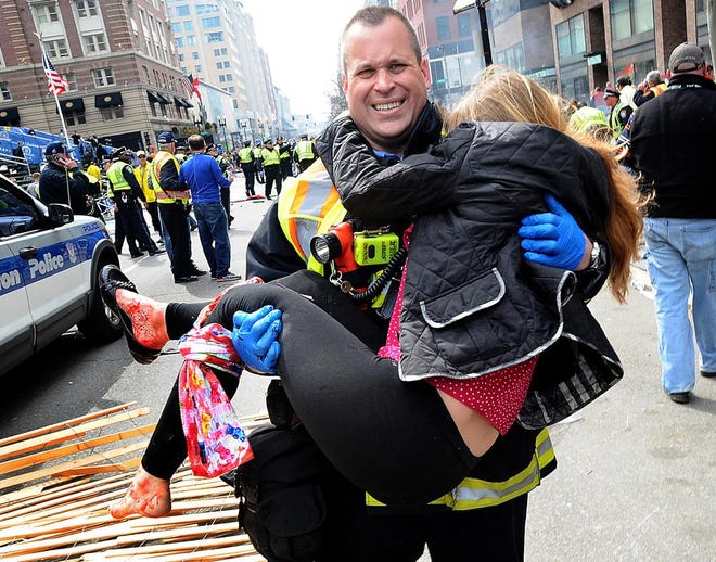 Boston Firefighter James Plourde carries an injured girl away from the scene of the Boston Marathon bombing on Boylston Street on Monday, April 16, 2013.