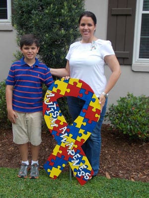 Cole Castrogovannie, 11, stands with his mother Trish Castrogovannie along with the logo for autism awareness.