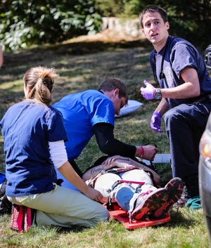 Holliston EMT Jordan Murawski, right, helps treat a person involved in a two vehicle crash at the intersection of Elm and Grove Streets in Holliston on Thursday. The crash involved a sedan and minivan and according to Sgt. Craig Denman, it's believed the driver of the sedan failed to stop at the intersection's stop sign and crashed into the minivan. Denman said both occupants of the sedan were transported to the hospital as well as the driver of the minivan with unknown injuries.