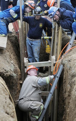 Dave Price, fire chief at Dow Chemical Co. and other emergency personnel use teamwork to put a strut in place during a trench-securing training exercise held in Bensalem on Thursday.
