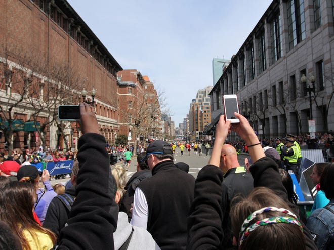 In this Monday, April 15, 2013, photo, spectators make pictures with camera phones during the Boston Marathon in Boston, before two bombs exploded at the finish line in an attack that killed 3 people and wounded over 170.
