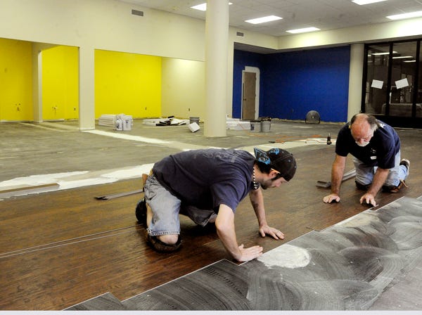 Joey Hobbs and Ken Moss lay new flooring as part of the Imagination Place expansion at the Hardin Center, Wednesday in Gadsden. The expansion is in the old dance studio area and will provide an additional 3,000 square feet of exhibit space for the Children's Museum. (Gadsden Times, Marc Golden)