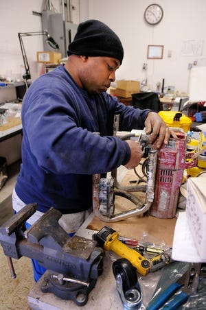 Markee Kinchen, an electronics technician at Micro Trap Corp. in Falls, works on repairing a paint sprayer.