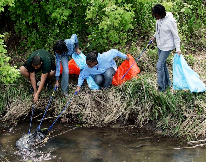 Kolten Luvert (from left), 15, Ketura St. Fleurose, 12, Debora St. Fluerose, 15, and Milca St. Fleurose, 14, work to pull a garbage bag out of the Kent Creek on Sunday, April 22, 2012, as a way to celebrate Earth Day on the grounds of Tinker Swiss Cottage Museum in Rockford.The kids are part of the Angelic Organics Learning Center.