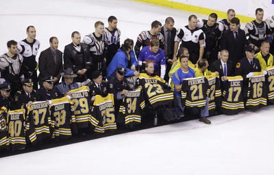 First responders, members of law enforcement and Boston Marathon officials hold Boston Bruins jerseys as they gather with members of the team, back, on the ice following an NHL hockey game against the Florida Panthers at the TD Garden in Boston, Sunday, April 21, 2013. In a change requested by fans, Bruins players presented their jerseys to some of those who offered help in the minutes and days following the marathon bombings on Monday. The Bruins defeated the Panthers 3-0. (AP Photo/Steven Senne)