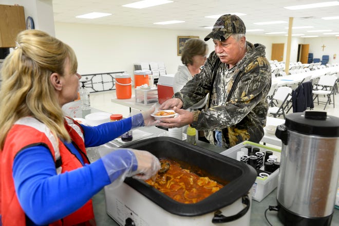 Ralph Atherton takes a dish of ravioli Tuesday from American Red Cross volunteer Julia Blankenship at the shelter set up at River's Edge United Methodist Church in Spring Bay. Flooding relief efforts statewide, including providing meals, are being coordinated by the Peoria chapter of the Red Cross.