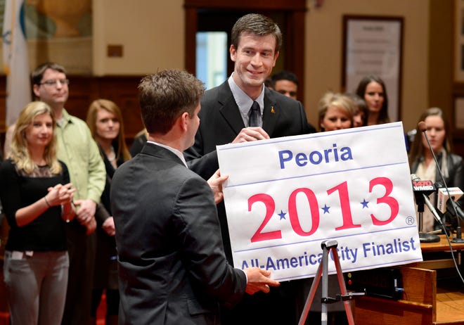 Tim Cundiff, the chairman of the Peoria Area Chamber of Commerce Young Professionals Organization, right, and Peoria City Councilman Ryan Spain unveil a sign indicating Peoria's inclusion as a finalist to become an All-America City. Peoria is one of 20 areas vying for 10 spots for the All-America City designation. A delegation will travel in June to Denver where representatives of each of the 20 will make their case for the designation.