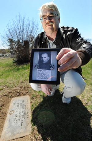 Military historian Jon Gawne at the grave of John Carr, a Framingham resident killed in WWII.
