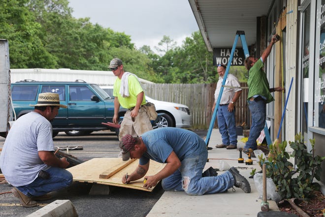 Contractors rebuild a storefront at a strip mall off of Airport Road in Panama City on Thursday.