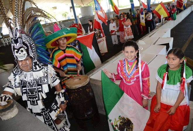 Representing Mexico, Juan Salinas (from left), wearing a ceremonial Aztec costume, prepares for the Parade of Flags with drummer Jorge Morales and flag bearers Lily Martinez, 10, and Leslie Hernandez, 9.