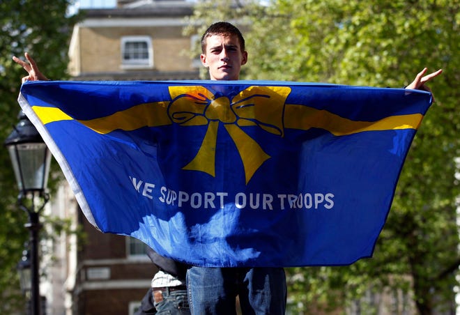 A protester holds up a banner as English Defence League supporters protest outside Downing Street in London in support of the British armed forces, after the brutal killing of an off-duty British soldier in a London street last week, Monday. (THE ASSOCIATED PRESS)