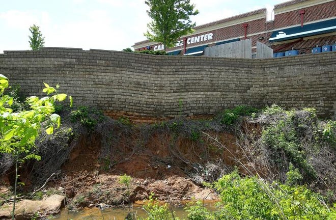 (John Clark/The Gazette) The retaining wall behind the AAA Car Care Center and the Sprint store on East Franklin Blvd. was damaged enough by the recent flood water that both busineses have been deemed unsafe to operate until repairs are made.