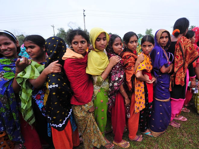 Bangladeshi garment workers employed at Rana Plaza, the garment factory building that collapsed, stand in a queue to receive wages from the Bangladesh Garment Manufacturers and Exporters Association in Savar, near Dhaka, Bangladesh, Tuesday, May 7, 2013.