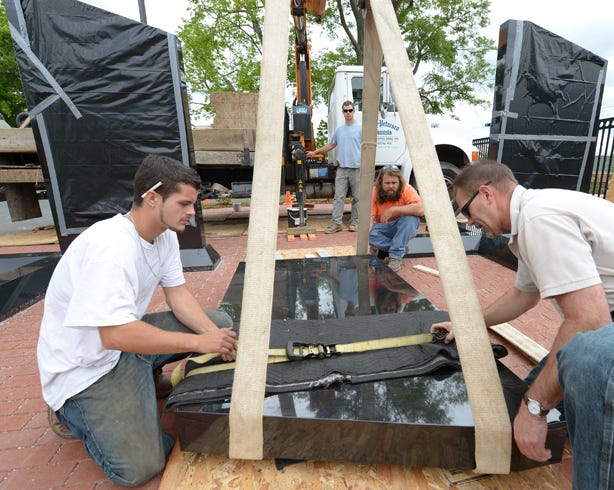 Eugene Petersen, right, and Coty Edmonds, left, of Askew-Petersen Monuments in Burlington work to secure one of the 2,500-pound granite monuments at the memorial site in Graham.
