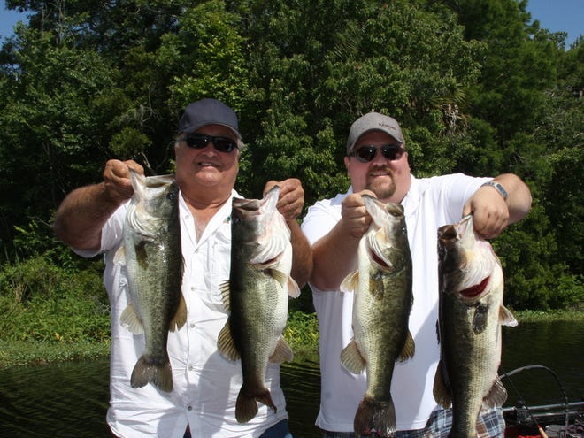 Andrew Maxwell (left), of Toronto, and Capt. Rick Rawlins of Highland Park Fish Camp with lunker bass caught on wild river shiners on the St. Johns River near DeLand.