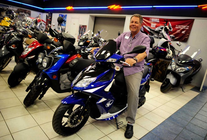 Street and Trail Motorsports General Manager David Heath sits on one of the many scooters for sale at the store in Evans.