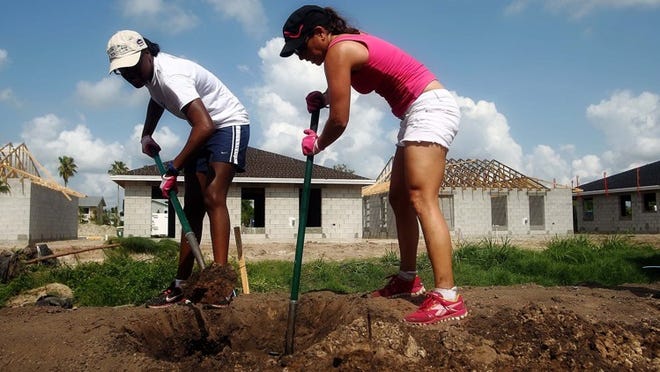 Rateesha Scott (left) of Cleveland and Jill Pritch of Palm Beach Gardens dig a hole for a tree in Jupiter’s Kennedy Estates II neighborhood during Habitat For Humanity’s National Women Build Week on Saturday. Pines and oaks were being planted behind the houses. ‘It’ll be a nice border,’ says Pritch, who has volunteered previously. ‘It is a great cause.’