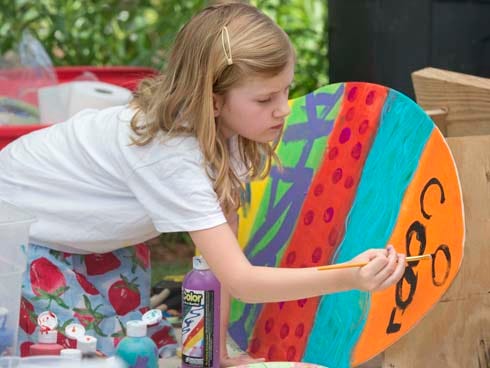 Hailey Brown paints her own skimboard Sunday at one of the booths in this year's ArtsQuest Arts and Music Festival held at WaterColor Inn and Resort.