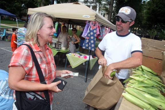 Sandy Hudson buys a bag of corn from Leif Hamrick at the Uptown Shelby Farmers Market. A new business, Farm to Front Porch, will deliver produce and other items to homes. (Star file photo)