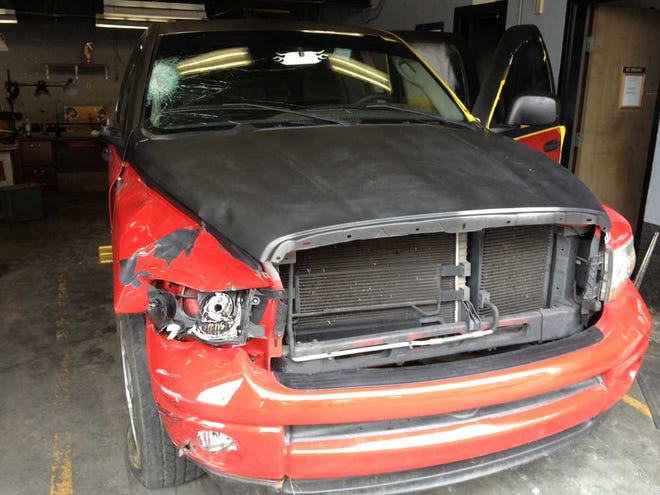 A damaged pickup that authorities believe was involved in the fatal hit-and-run of a cyclist sits in a garage bay at the Richmond County Sheriff's Office.