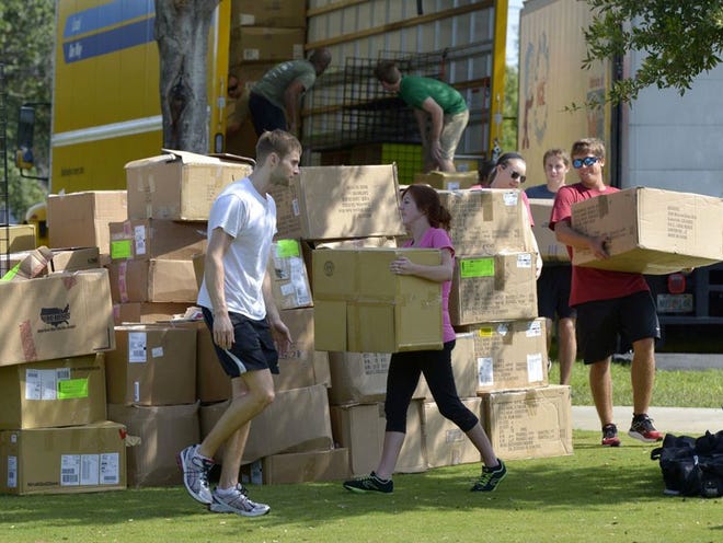 Fit2Run staff unload boxes of merchandise from a truck at Lake Eva Park in Haines City on Thursday. Event staff and vendors are busy getting ready for this weekend's 70.3 Ironman Florida event.