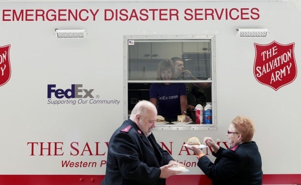 Salvation Army Capts. Henry Thibault, left, and Irene Thibault receive sandwiches served from a disaster response unit canteen vehicle Wednesday at the 911th Air Force Reserve base in Moon Township. Inside the vehicle is Colleen Ferrari of FedEx, which donated the response unit.