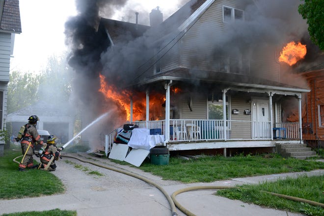 Firefighters battle a blaze Friday evening at 828 E. Maumee St. in Adrian.