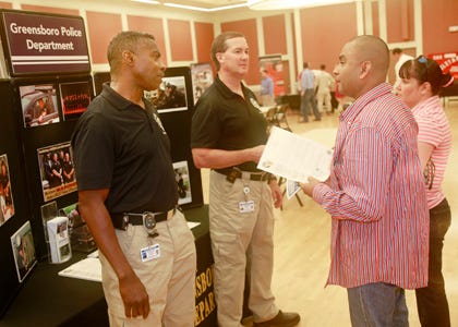 William Phifer and Harold Scott, with the Greensboro Police Department speak to Marcos Tapia and his wife Claudia Tapia at the Career Expo aboard Camp Lejeune Thursday afternoon.