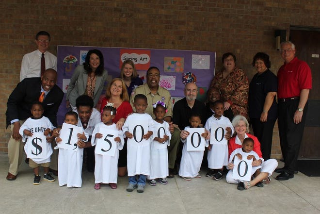 Children who receive services from The Arc Baton Rouge hold signs to represent the donation amount that ExxonMobil made to Capital Area United Way in its 2012 campaign contribution. Along with the children are representatives from several CAUW partner agencies, including AMIKids Baton Rouge; Boys & Girls Club of Greater Baton Rouge; Boy Scouts of America, Istrouma Area Council; Catholic Charities; Girl Scouts Louisiana East; Greater Baton Rouge Food Bank; Hope Ministries; Salvation Army; The Y; and YWCA Greater Baton Rouge. Far left, standing: Richard Williams, interim President/CEO for Capital Area United Way; far right, standing: Paul Stratford, ExxonMobil Chemical Sites Manager.